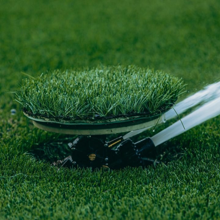 Close-up of an automatic sprinkler watering a lush green lawn, showcasing irrigation system.